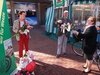  v.l.n.r.: Rita Pöppel und Johannes Bauer vom Vorstand des Weezer Werberings überreichen Rosen auf dem Weezer Wochenmarkt. 