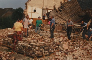 Sloopwerkzaamheden, 1990. Vrijwilligers maken de klinkers goed schoon en stapelen ze op