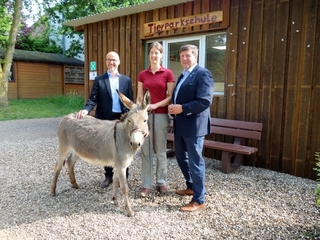 von links nach rechts: Dirk Krämer, Marie-Christine Kuypers und Bürgermeister Ulrich Francken freuen sich über den Besuch der Eseldame 'Giny' vor der Tierparkschule im Tierpark Weeze