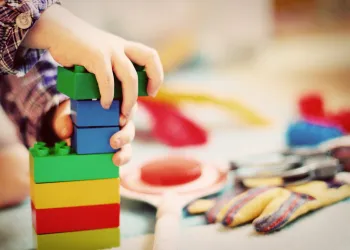 Die Hand eines Kindes, welches mit Legosteinen spielt.