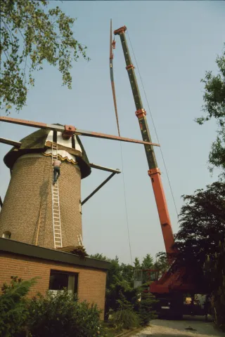 Neuen Flügel werden mit Hilfe eines Krans angebracht Ein Kran hebt den neuen Flügel in der Luft direkt neben der Windmühle