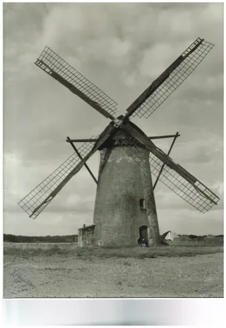 Turmwindmühle um 1950 Eine Windmühle auf freiem Feld mit einer Person in der Eingangstür